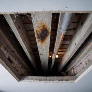 Water stain on an attic roof joist above a bathroom showing a hidden moisture source