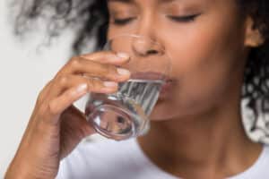 Woman drinking a glass of water after ingesting mold