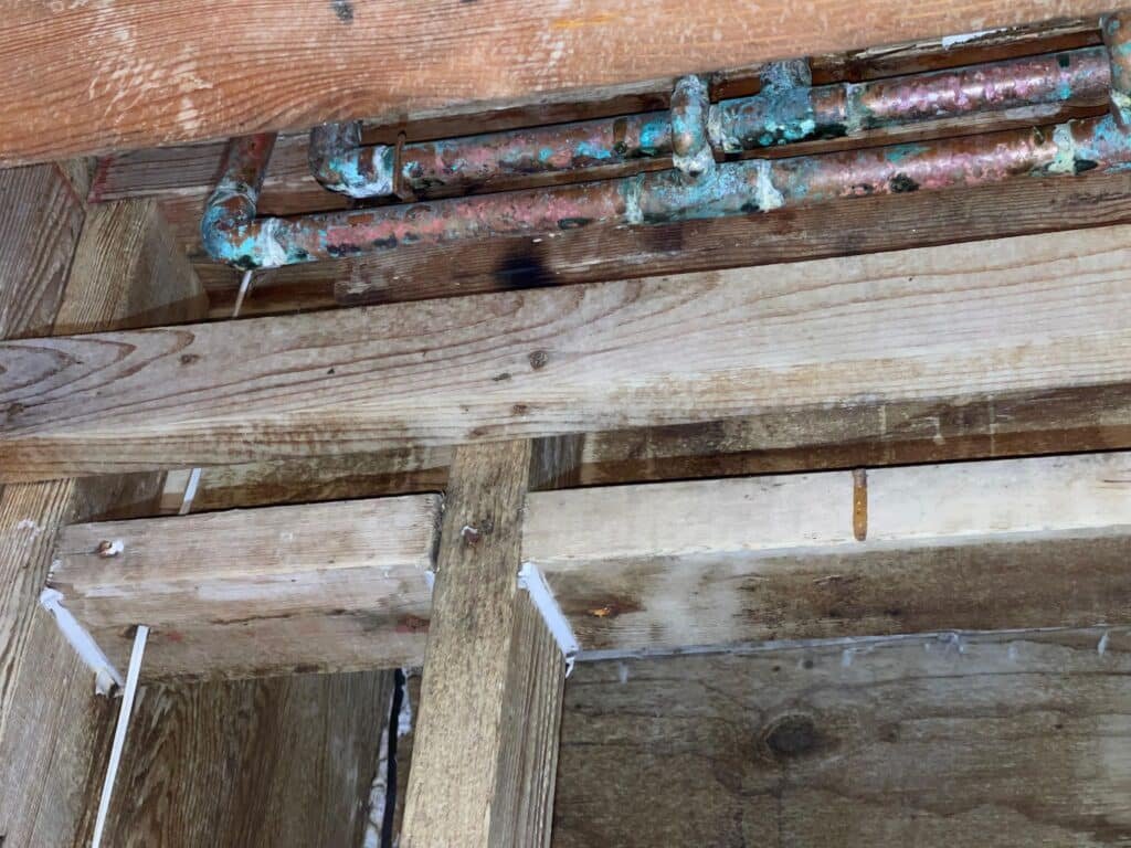 Framing and plumbing lines exposed after water damage in a Houston home