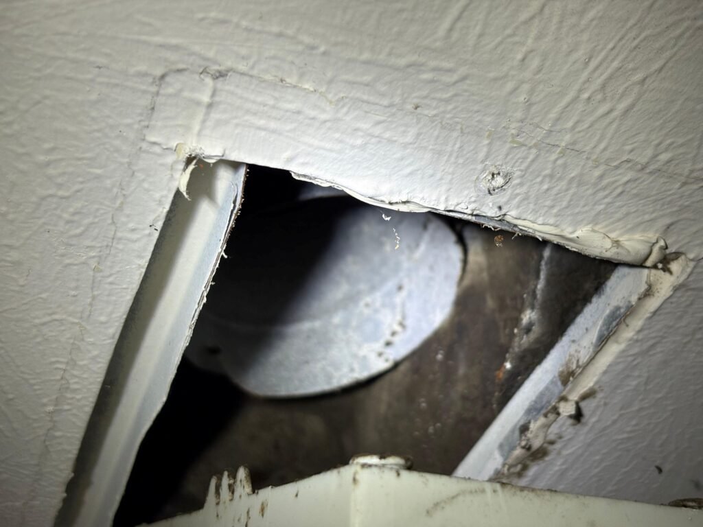 Duct interior exposed behind a ceiling register during a mold inspection