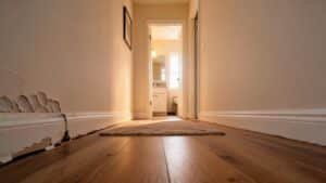 Bubbling paint and a loose baseboard in a hallway, early warning signs of mold behind walls in a Houston home.